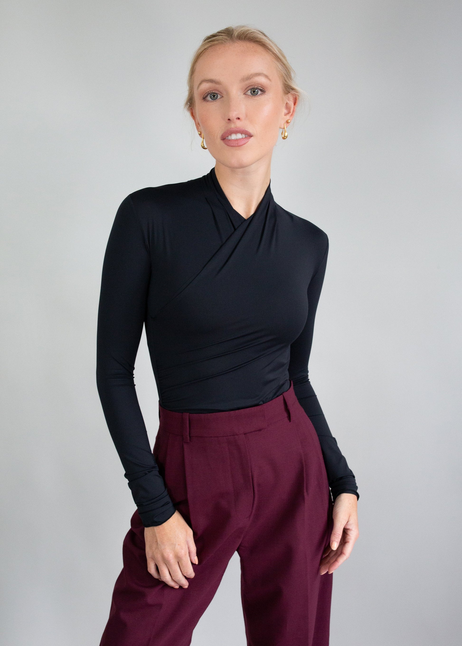 Kobieta w czarnej bluzce z długim rękawem i bordowych spodniach