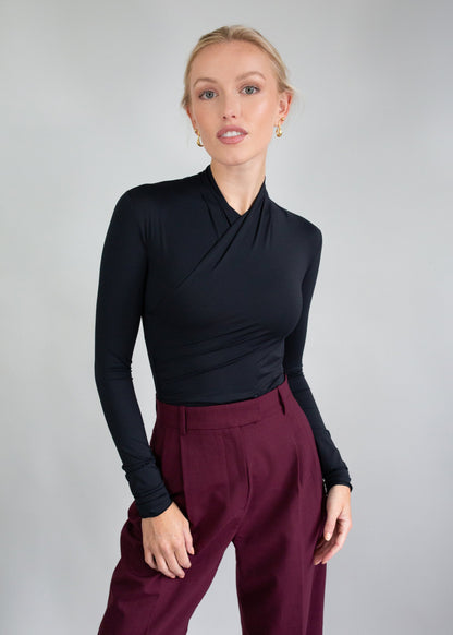 Kobieta w czarnej bluzce z długim rękawem i bordowych spodniach